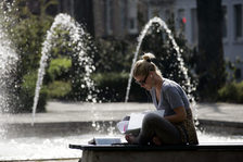 Lernende junge Frau vor einem Brunnen