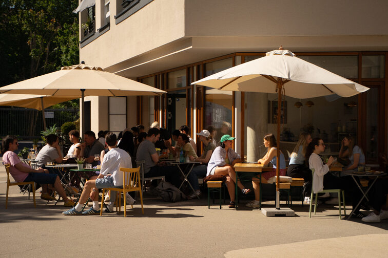 Bir kafede şemsiyelerin altında oturan insanlar