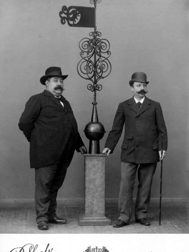 zwei Männer neben der Wetterfahne des Hauses zum Kuckuck