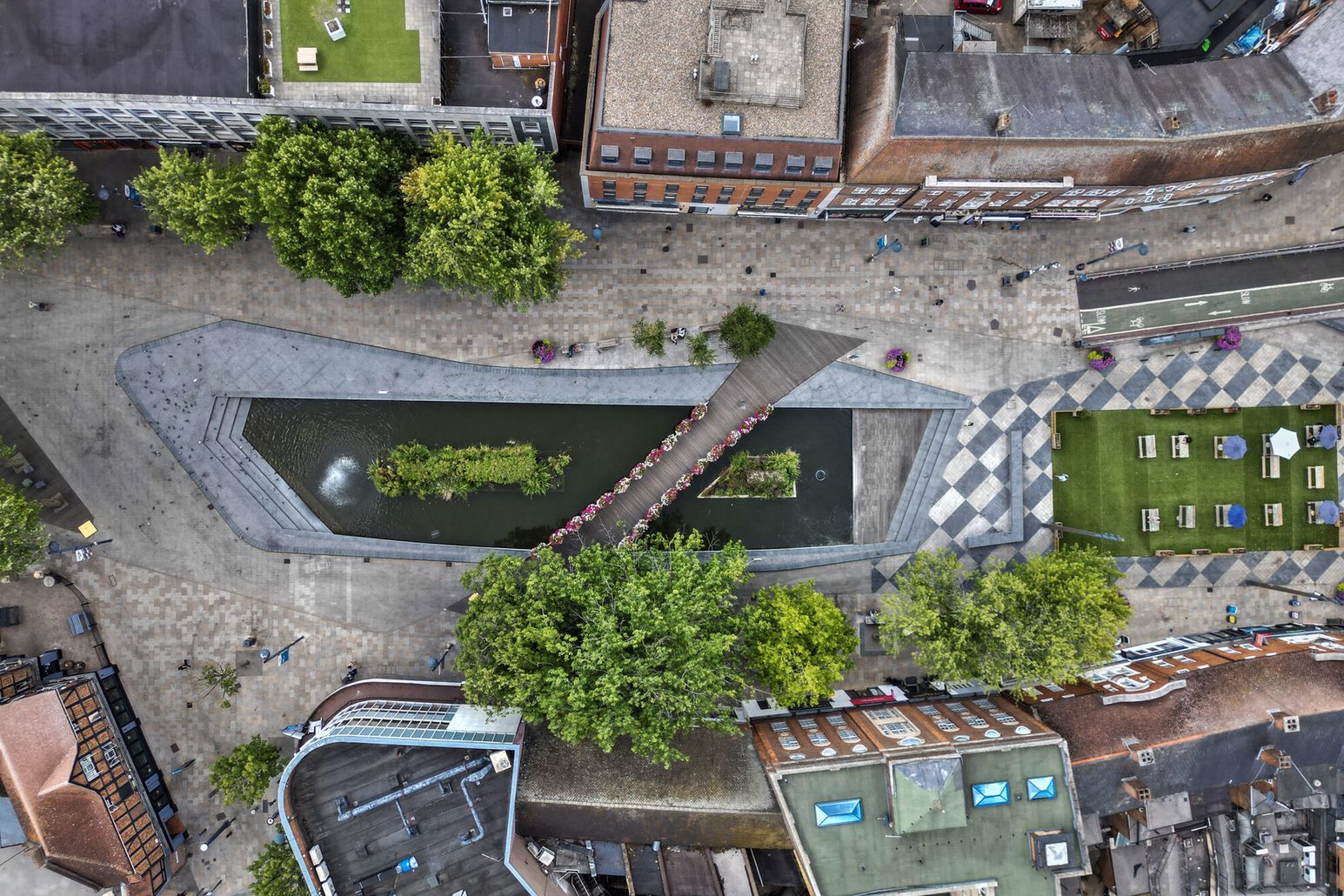 A bird's-eye view of a square with a small pond and bridge in Watford