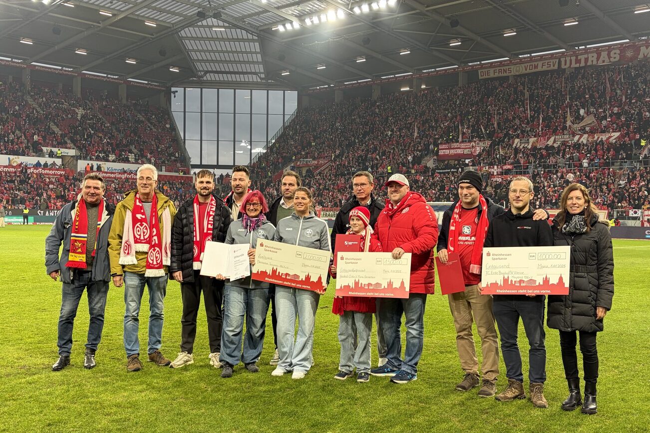 Jurymitglieder und Presiträger stehen auf dem Rasen im Stadion