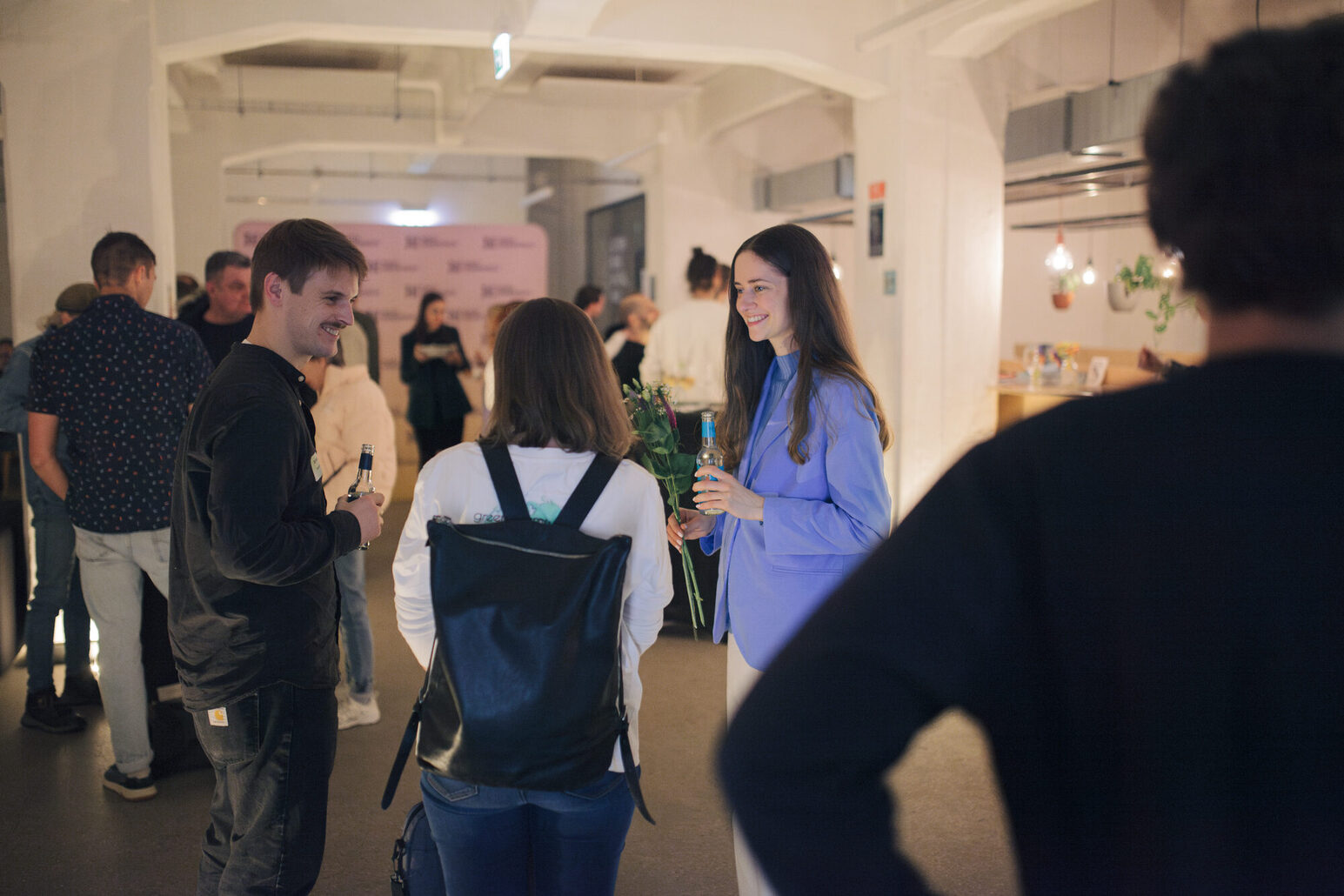 Eine Gruppe von Menschen unterhält sich angeregt. Im Vordergrund steht ein Mann, mit dem Rücken zum Betrachter