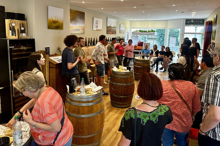 Menschen bei einer Weinprobe in einem Raum mit Weinfässern