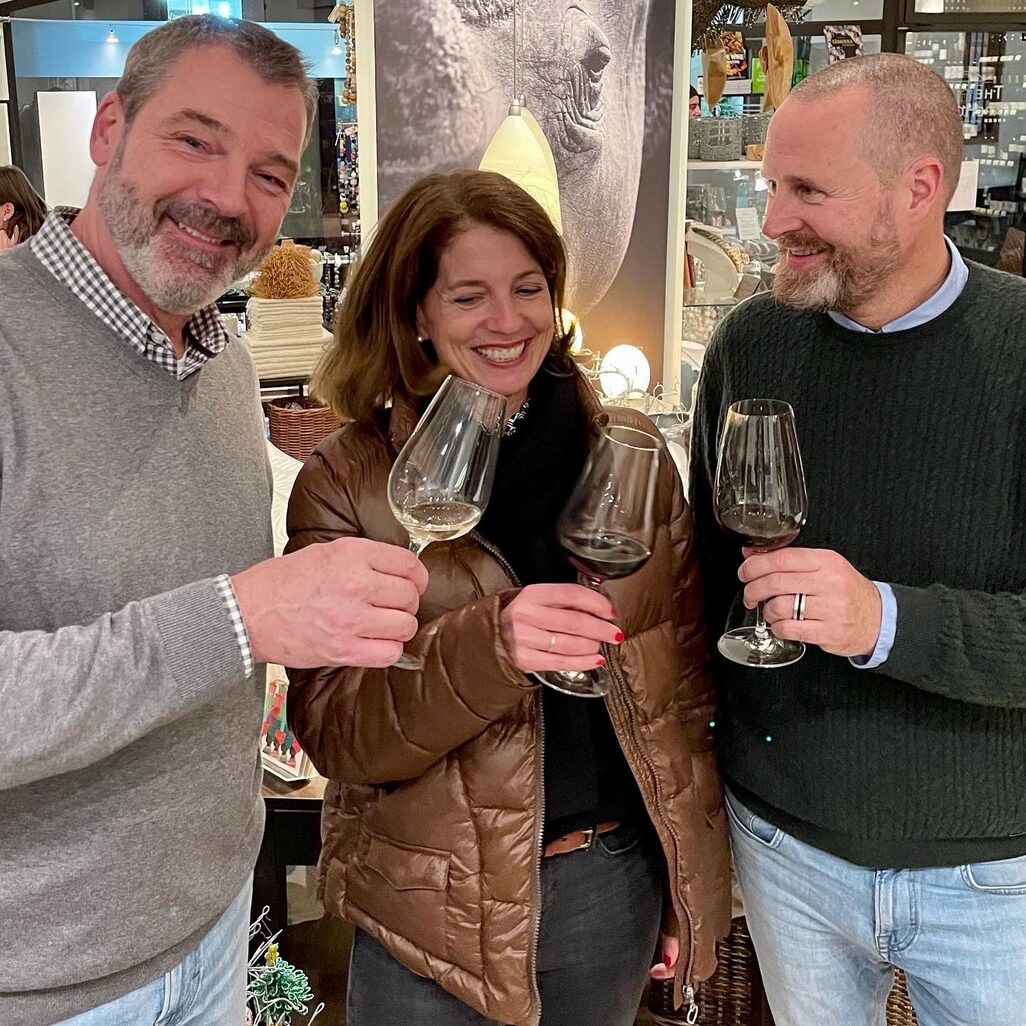 Two gentlemen and a lady clink glasses of wine