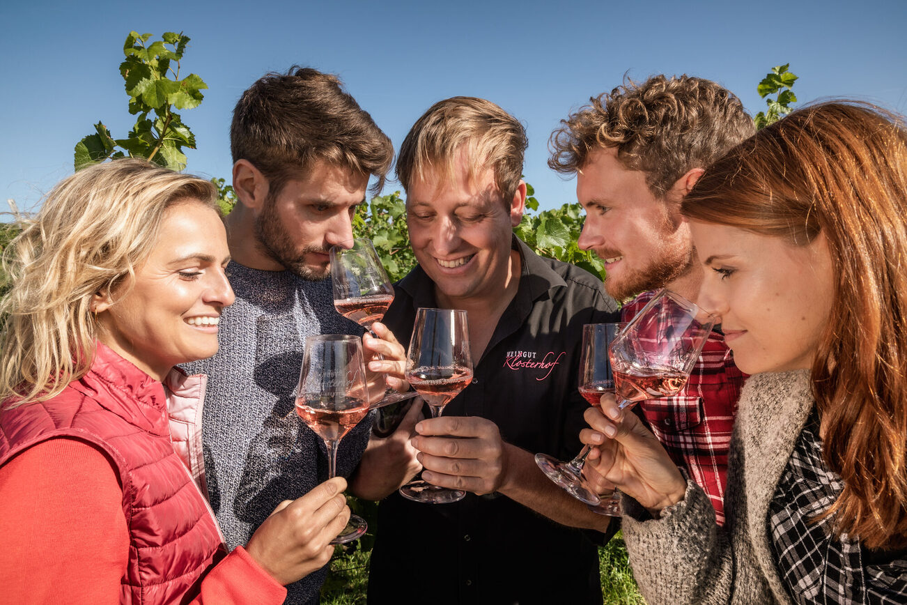 A group tasting wine in the vineyard.