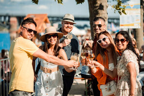 Menschen am Rheinufer in Mainz mit einem Glas Wein in der Hand © mainzplus Citymarketing / Maximilian Klapdar