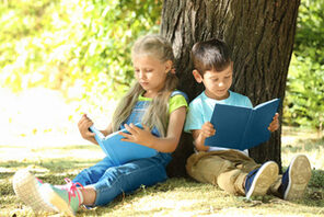 Zwei Kinder sitzen draußen und lesen © Adobe Stock / Africa Studio