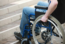 Mensch im Rollstuhl am Fuß einer Treppe