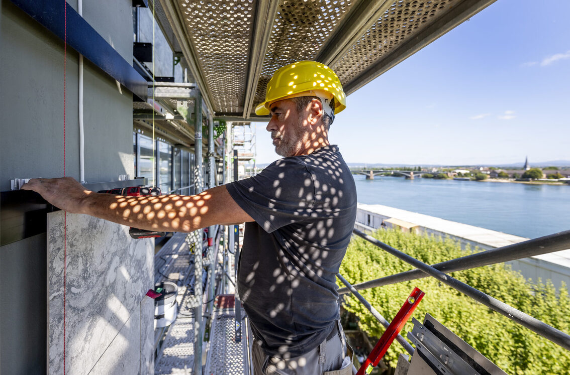 Ein Bauarbeiter arbeitet auf einem Grüst an der Fassade des Rathauses