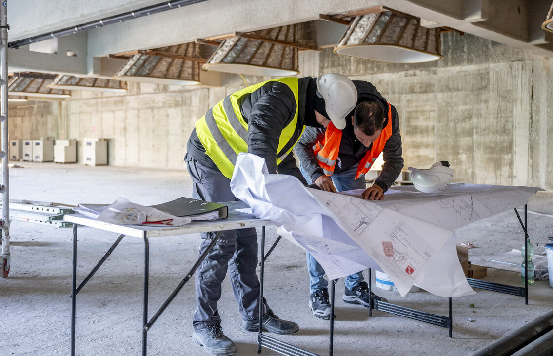 Due operai edili studiano il progetto dell'edificio.