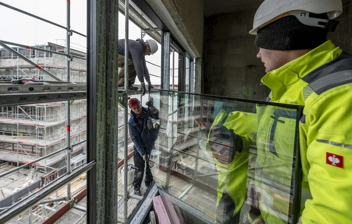 Tre operai edili con il vetro di una finestra.