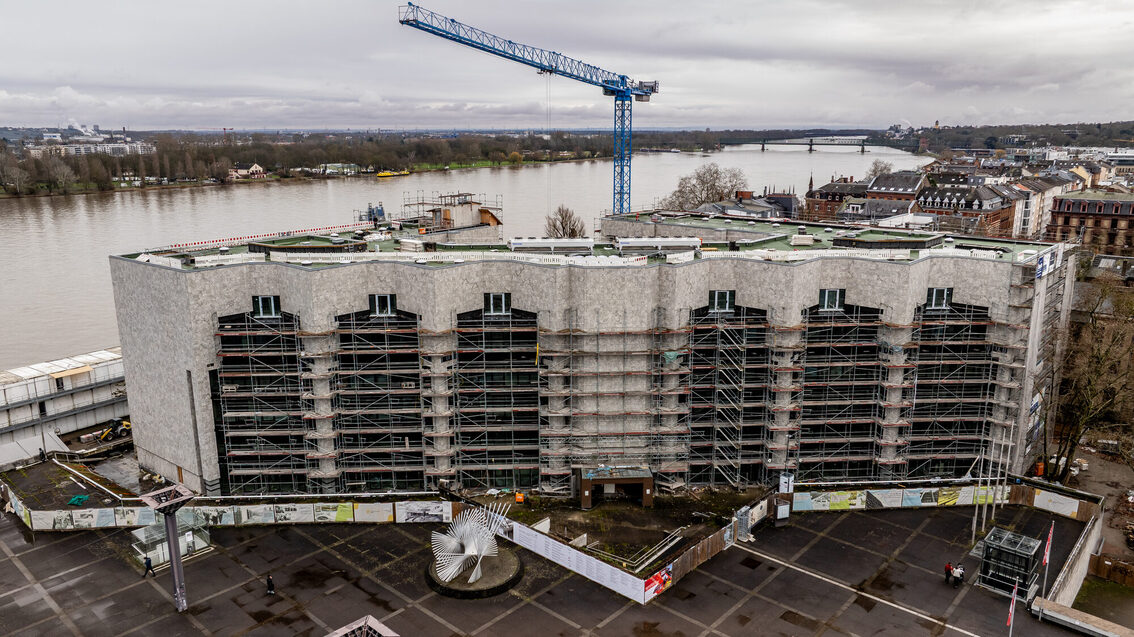 Blick in Richtung Rhein auf das Rathaus von oben, an dem viele Baugerüste stehen