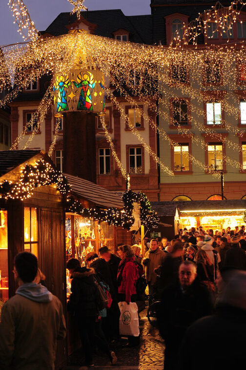 Heunensäule mit festlicher Haube und Lichterkette vor den Markthäusern