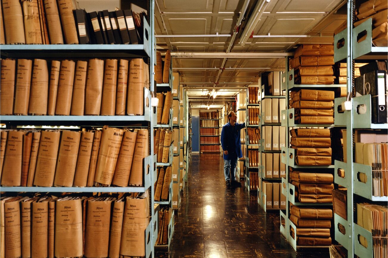 In der Mitte ein Gang. Rechts und Links davon Regale mit alten Unterlagen.