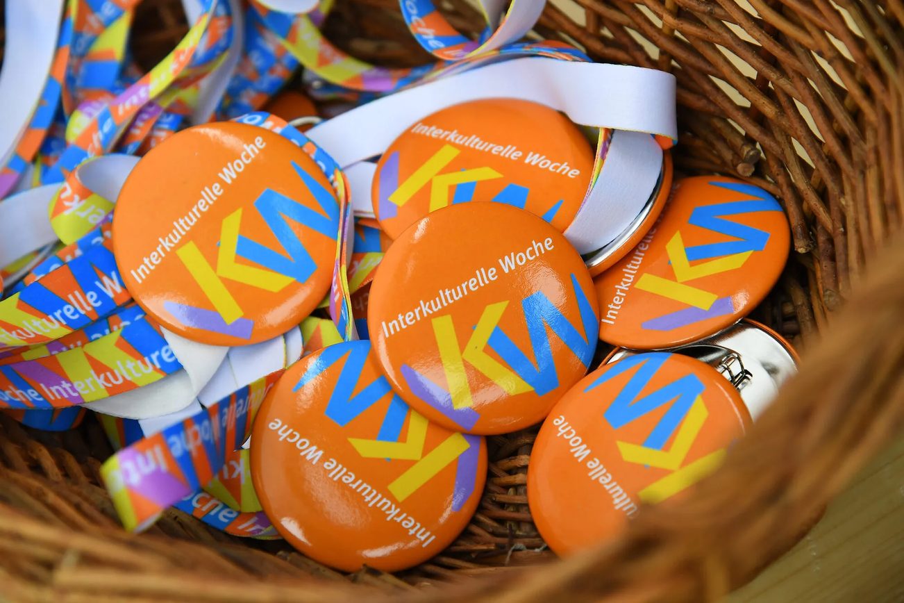 Panier en osier tressé rempli de badges orange de la "Semaine interculturelle