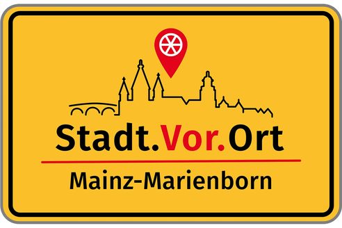 Cartello giallo di ingresso al comune di Mainz-Marienborn, modificato con il profilo dello skyline di Magonza, la ruota di Magonza e la scritta "Stadt.Vor.Ort", il nuovo formato di partecipazione civica.