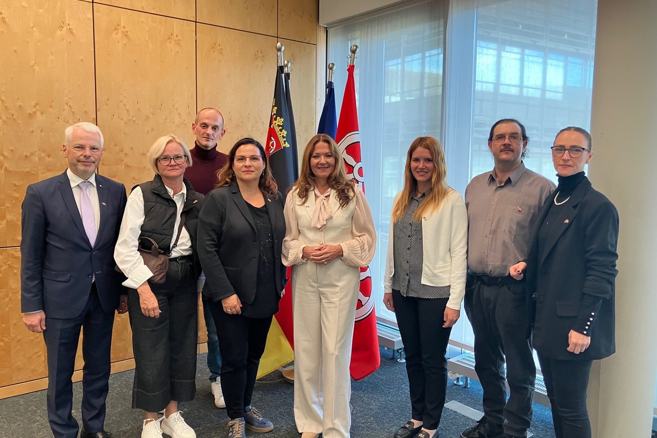 Group photo taken in an office in front of flags.