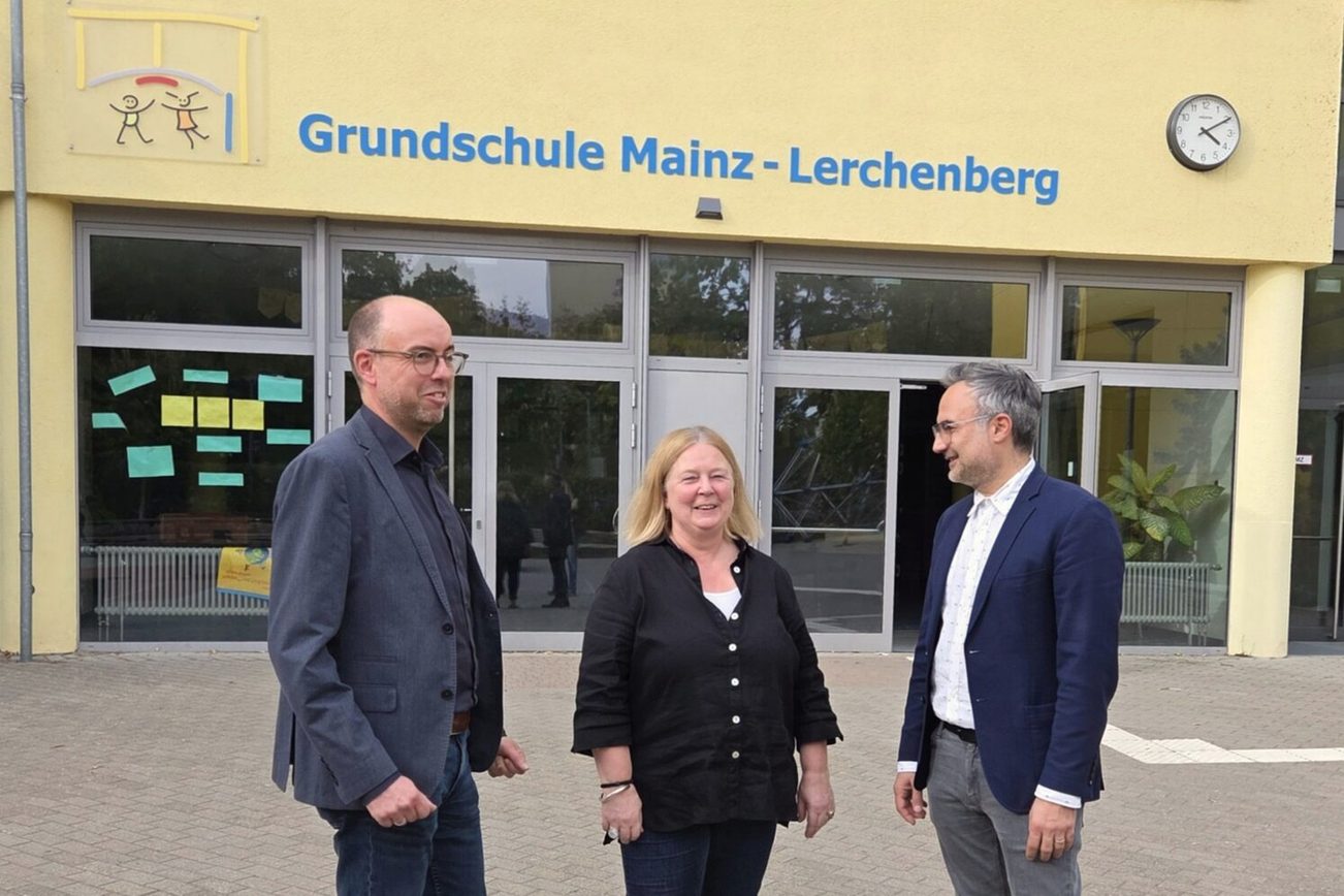 Christian Hoffmann, responsabile del dipartimento Clienti e Pubbliche Relazioni della Mainzer Mobilität, Susanne Millen, preside della scuola elementare di Magonza-Lerchenberg, e Ata Delbasteh, assessore all’istruzione della città di Magonza, si trovano davanti all’edificio scolastico con la scritta “Scuola elementare di Magonza-Lerchenberg”