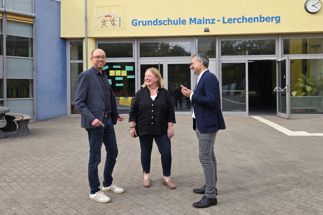 Christian Hoffmann, responsabile del dipartimento Clienti e Pubbliche Relazioni della Mainzer Mobilität, Susanne Millen, preside della scuola elementare di Magonza-Lerchenberg, e Ata Delbasteh, assessore all’istruzione della città di Magonza, si trovano davanti all’edificio scolastico con la scritta “Scuola elementare di Magonza-Lerchenberg”