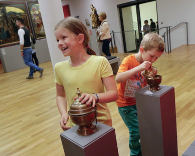Zwei Kinder betrachten neugierig die Hands-on-Angebote im Landesmuseum