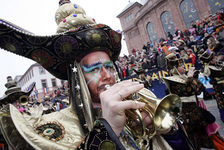 Ein Guggemusiker im schwarz-goldenem Kostüm beim Rosenmontagszug