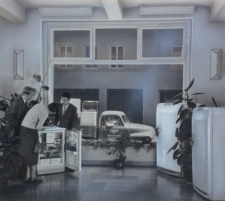 Frigidaire-Kühlschränke werden im Opelwerk in Rüsselsheim produziert. Der Blick aus dem Ausstellungsraum auf die Straße richtet sich auf einen Opel-Blitz, der Kühlschränke transportiert.