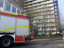 Feuerwehrauto mit der Hochhausfront im Hintergrund.