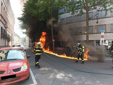 Einsatzkräfte vor der brennenden Kehrmaschine.