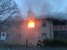 Flammen dringen aus einem Fenster im ersten Stock heraus.