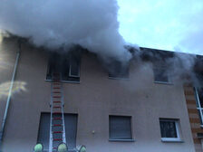 Rauch dringt aus einem Fenster im ersten Stock aus.