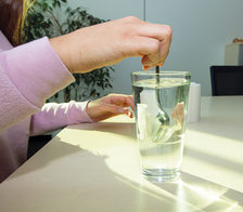 Ein Stück Toilettenpapier wird in einem Glas Wasser verrührt.