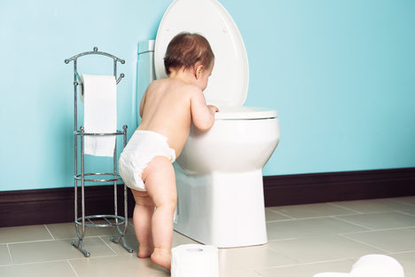 Ein Baby, das neugierig in eine Toilette blickt.