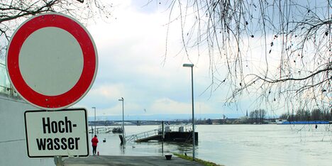 Ein Hinweisschild am überfluteten Rheinufer.