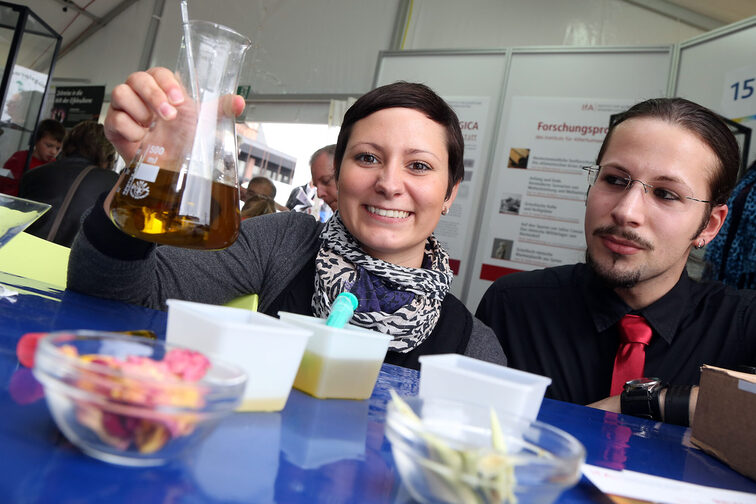 Eine junge Frau hält einen Kolben mit Flüssigkeit hoch