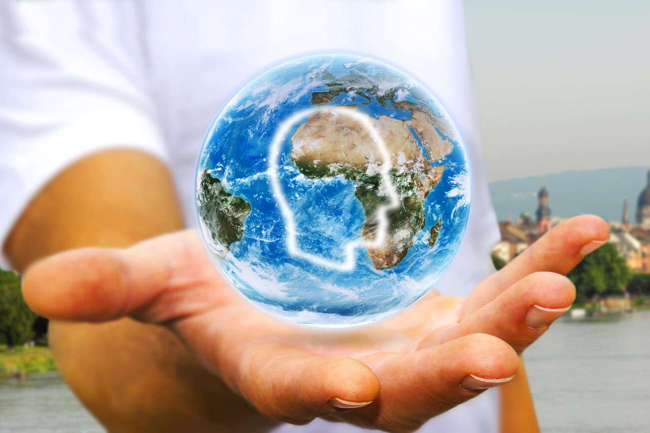 Eine Hand hält eine Weltkugel, im Hintergrund ist Mainz zu sehen.
