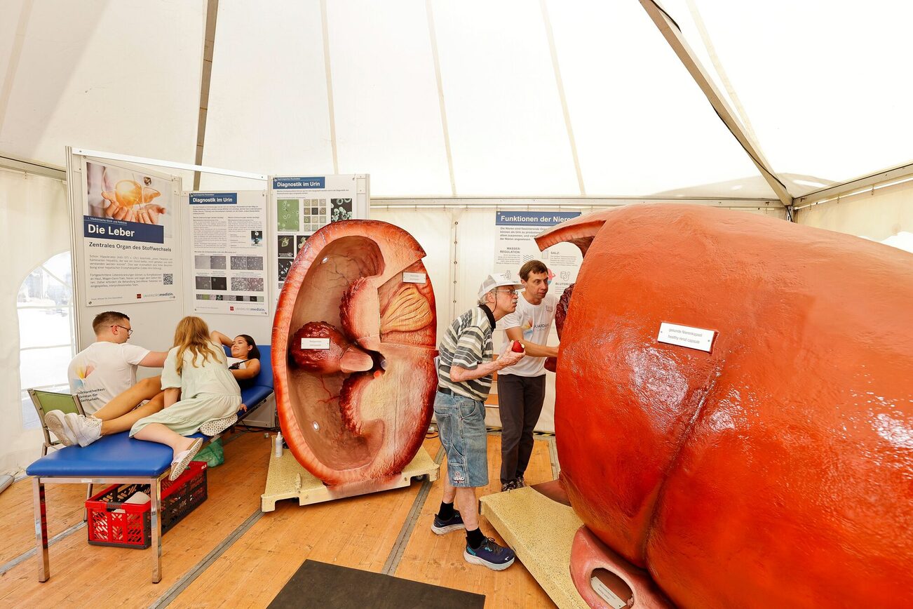 Mehrere Erwachsene und Kinder betrachten einen leuchtenden Kasten.