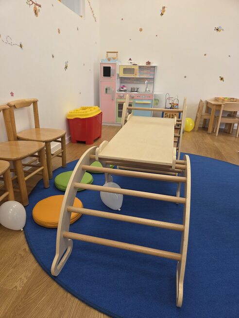 Attrezzature ludiche negli asili nido: arco per arrampicarsi, cucina per bambini, area per sedersi.