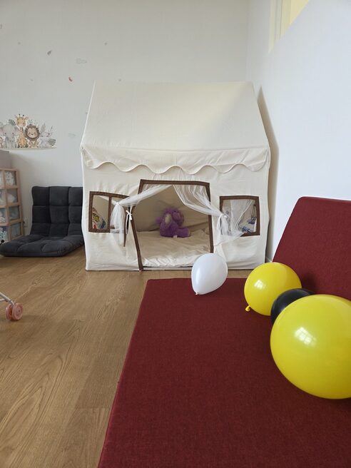 Cuscini in primo piano, una tenda da gioco bianca sul fondo dell'immagine.