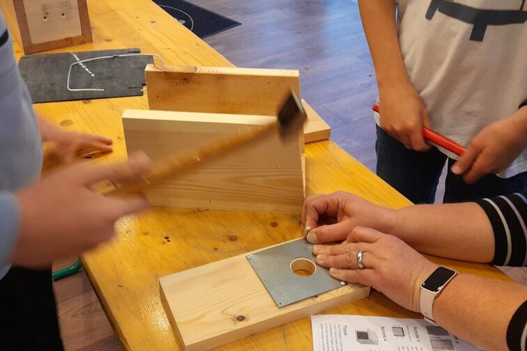 Personen bauen einen Gartenschläfer-Nistkasten