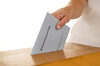 Wahlumschlag wird von einer Hand in eine Wahlurne geworfen